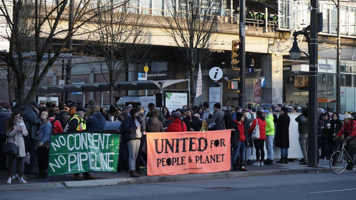 Des manifestants tiennent des affiches contre les projets énergétiques Coastal GasLink et Trans Mountain.