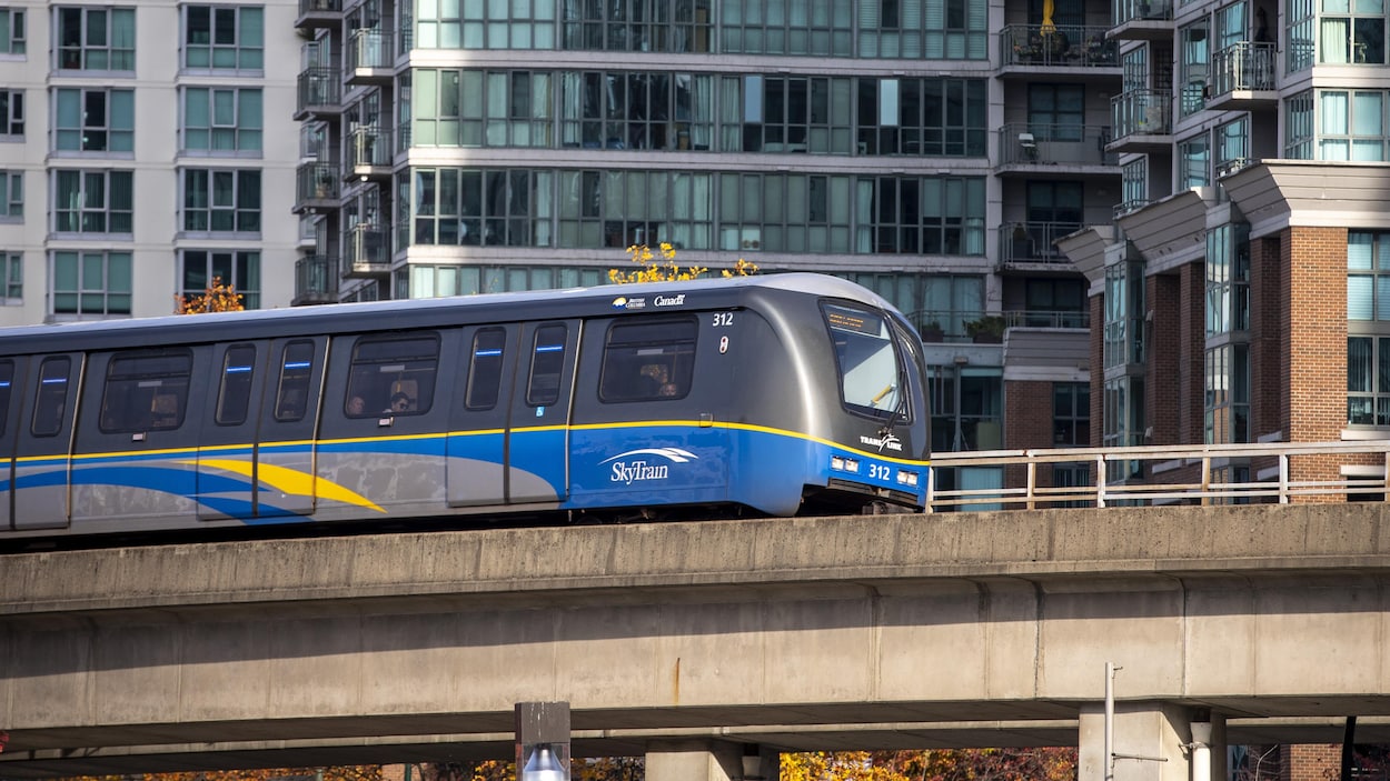 Une rame du métro Skytrain passant devant des immeubles résidentiels à Vancouver.