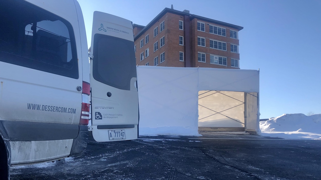 Un camion de transport médical adapté devant un hôpital.