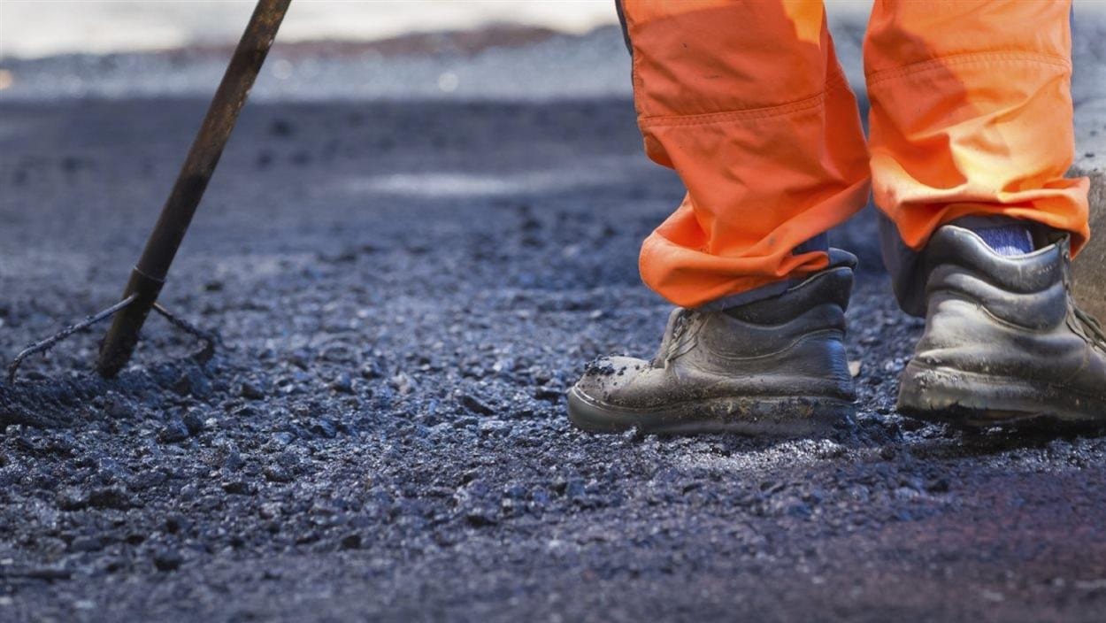 Un travailleur en train de poser de l'asphalte.