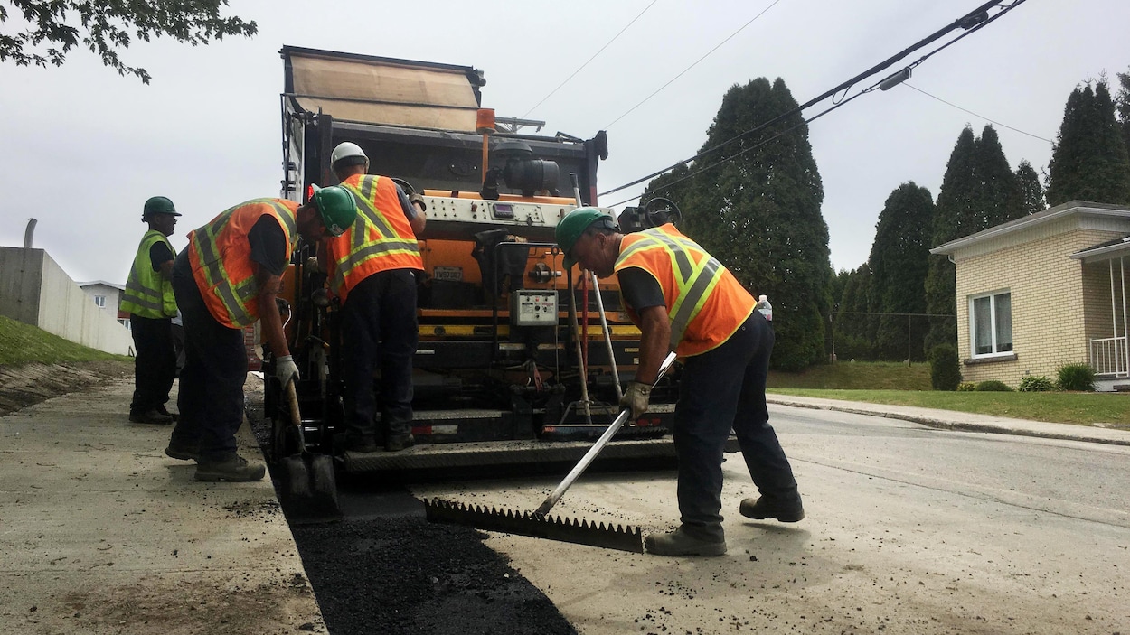 Des employés municipaux en train d'asphalter une rue.