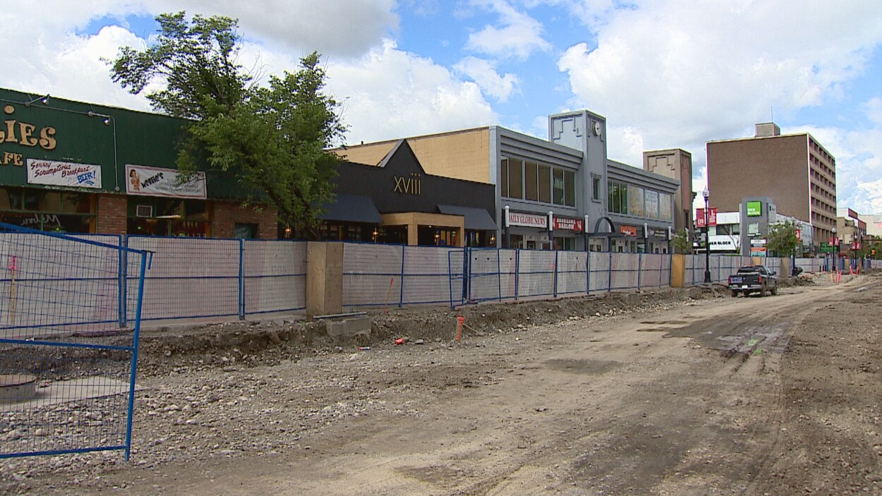 Une rue bloquée par les travaux. Des commerces sont visibles derrière la clôture.