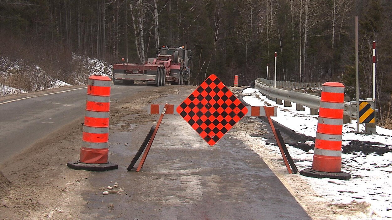Des cônes oranges bloquent l'une des deux voies de la route. Des cônes oranges bloquent l'une des deux voies de la route.