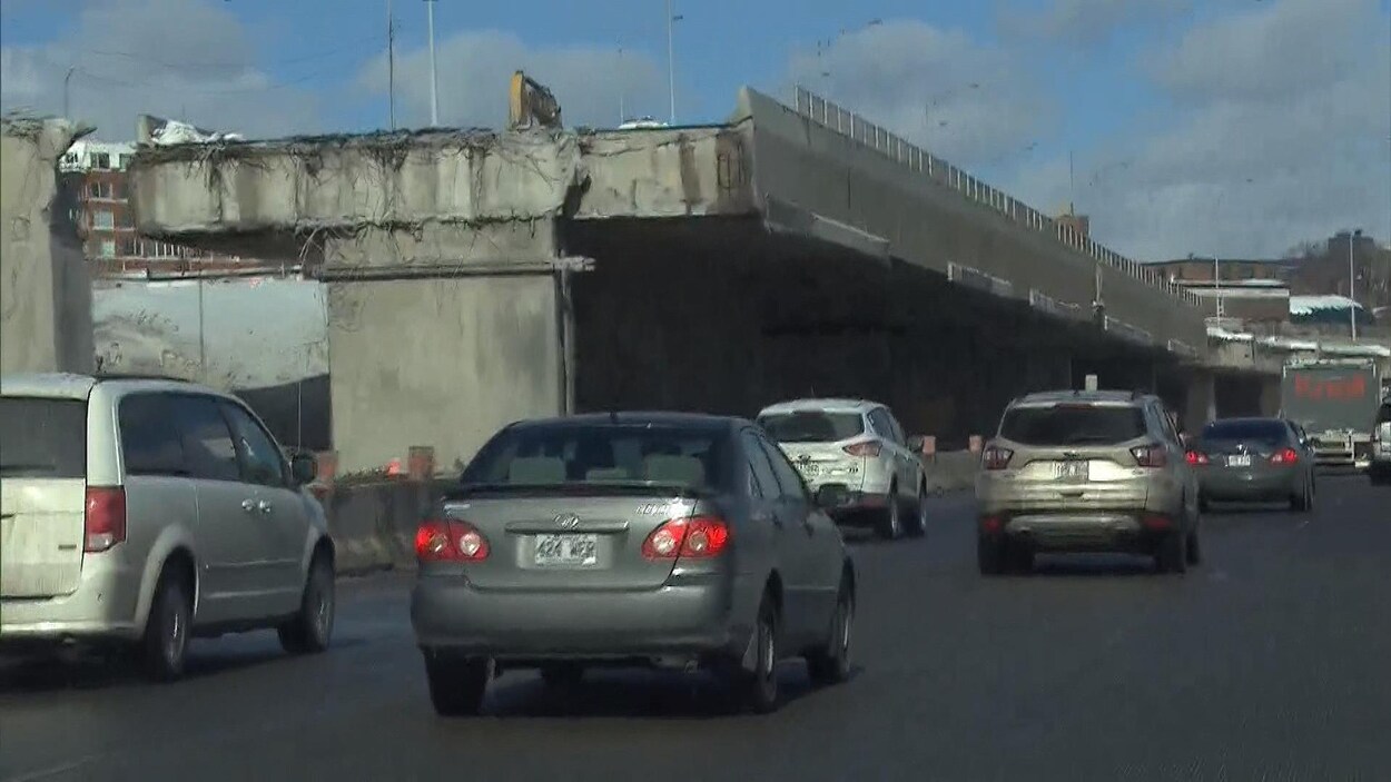 Des autos circulent à côté d'une voie surélevée à moitié démantelée. Des autos circulent à côté d'une voie surélevée à moitié démantelée.