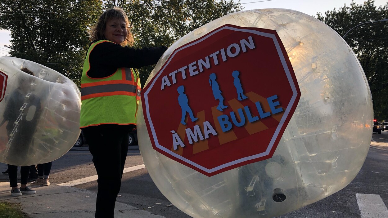 Une femme installe une bulle gonflable sur un enfant en bordure de la route à Alma.
