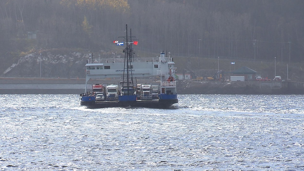 Un traversier flotte sur l'eau et semble rempli de véhicules lourds. Un traversier flotte sur l'eau et semble rempli de véhicules lourds.