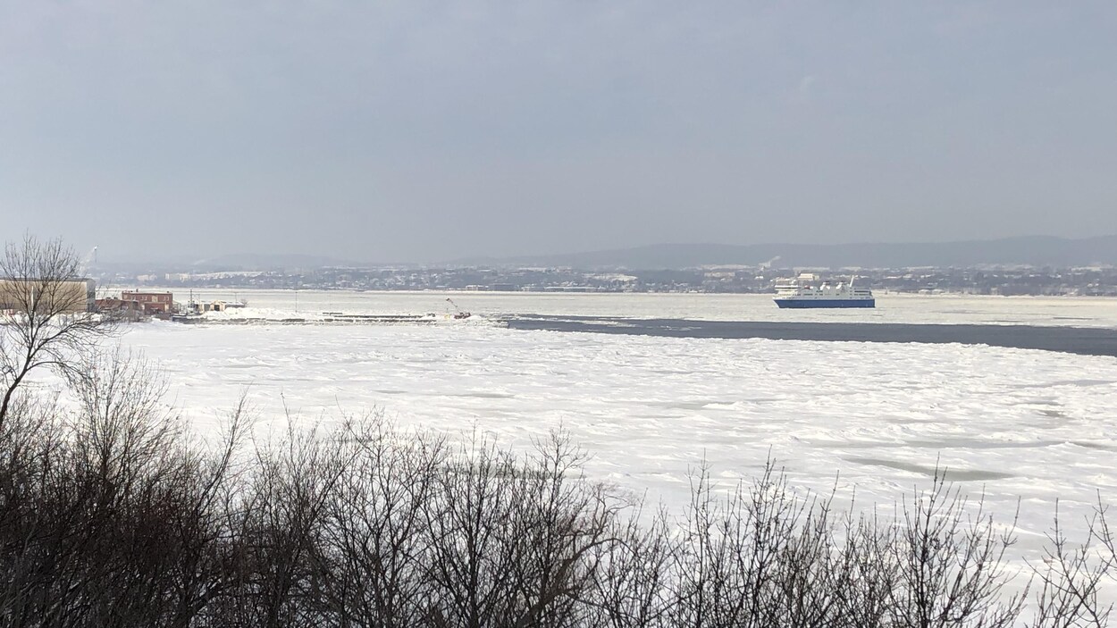 Vu de loin, le navire avance sur l'eau glacée.