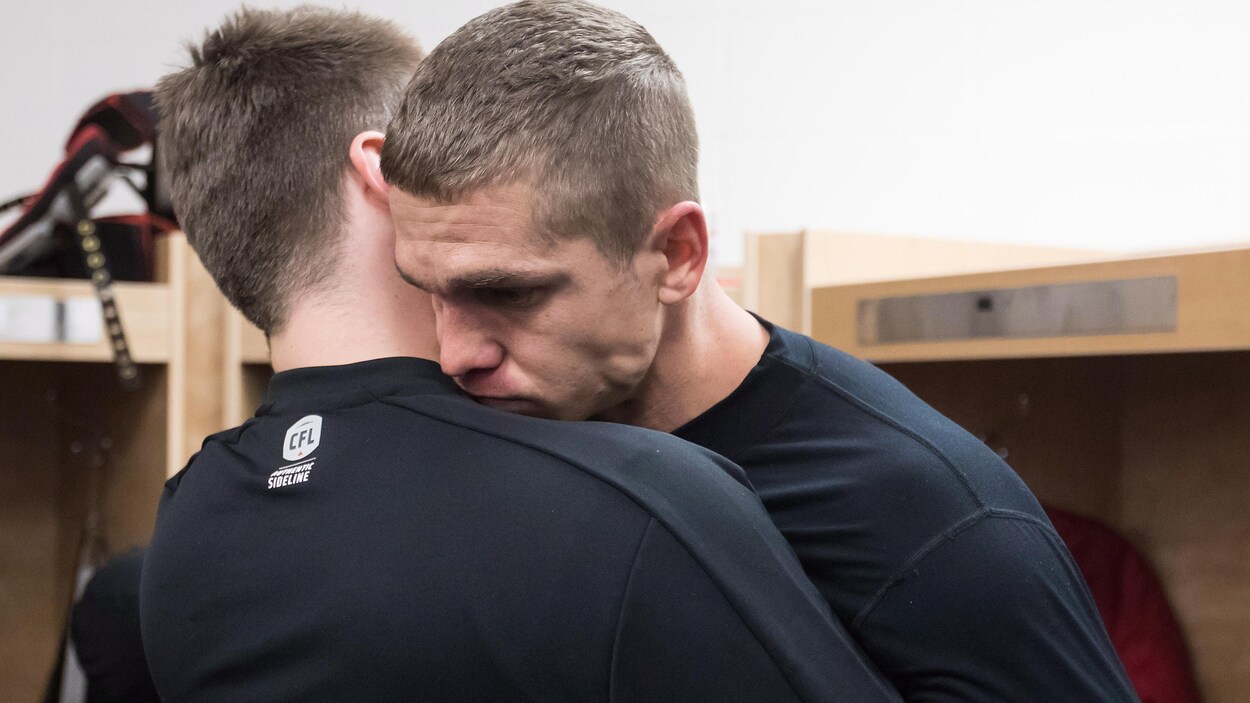 Deux hommes se consolent en se prenant dans leurs bras.