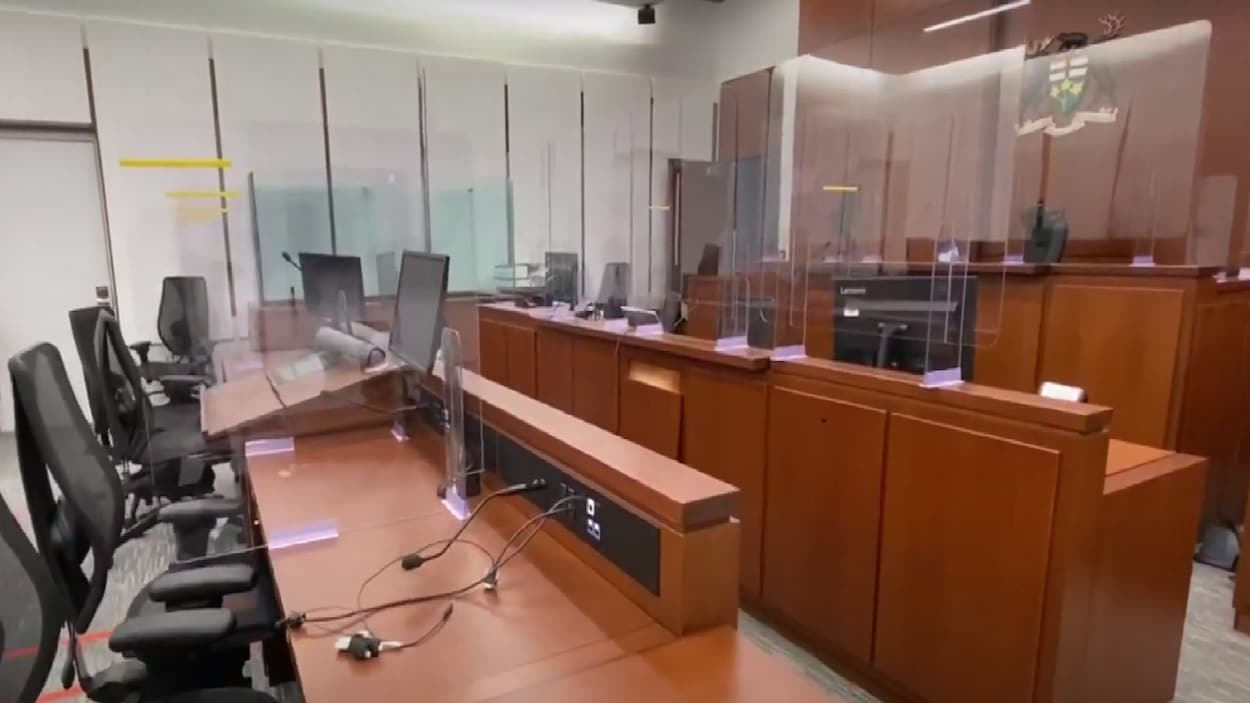 Une salle d'audience avec des plexiglas autour des bureaux.
