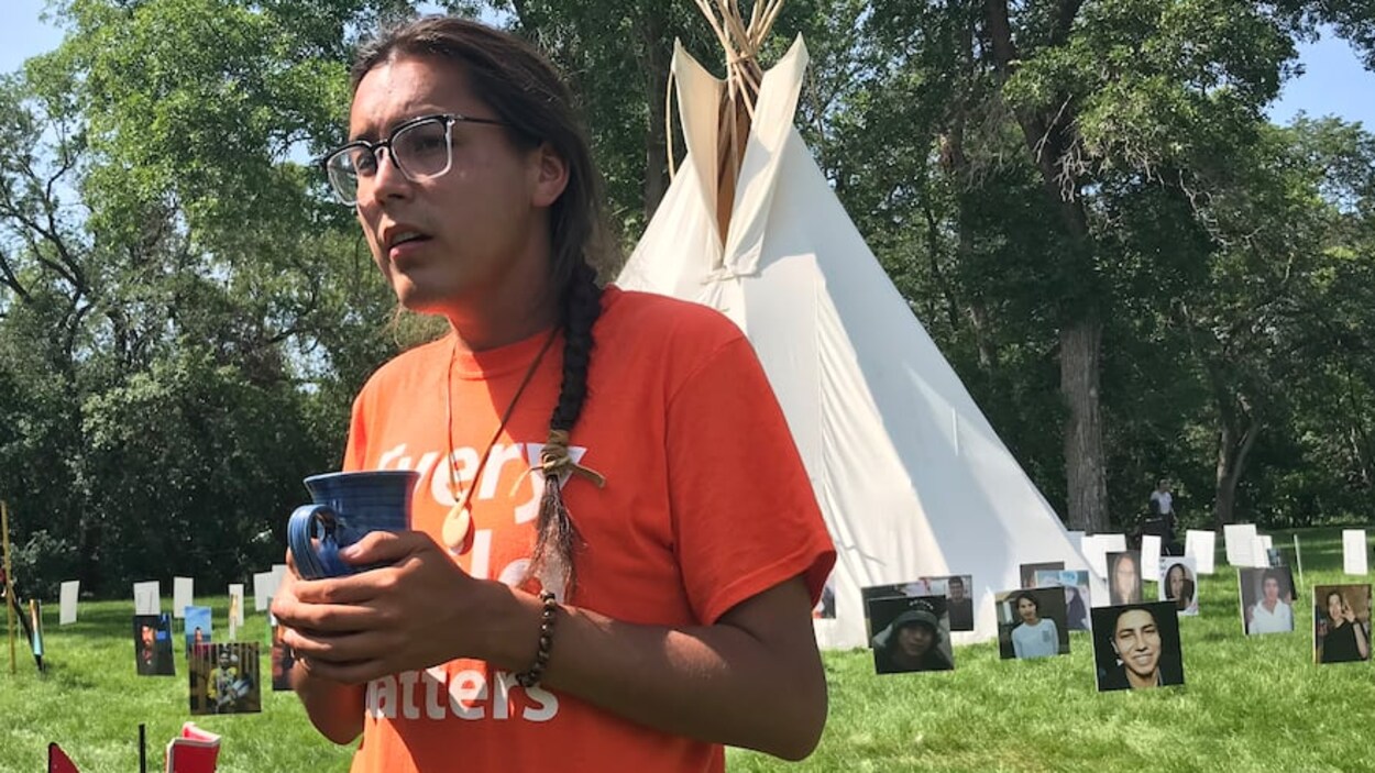 Tristen Durocher est debout devant son tipi avec une tasse dans les mains.