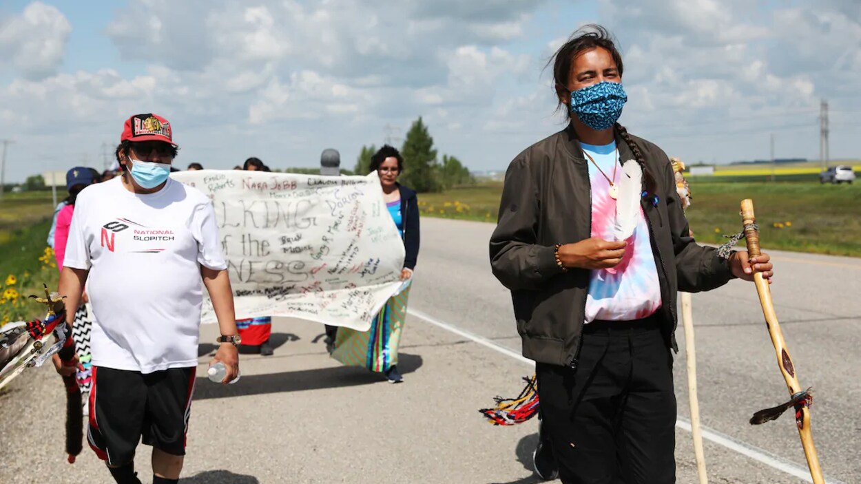 Tristen Durocher marche le long d'une route avec des supporteurs qui le suivent.