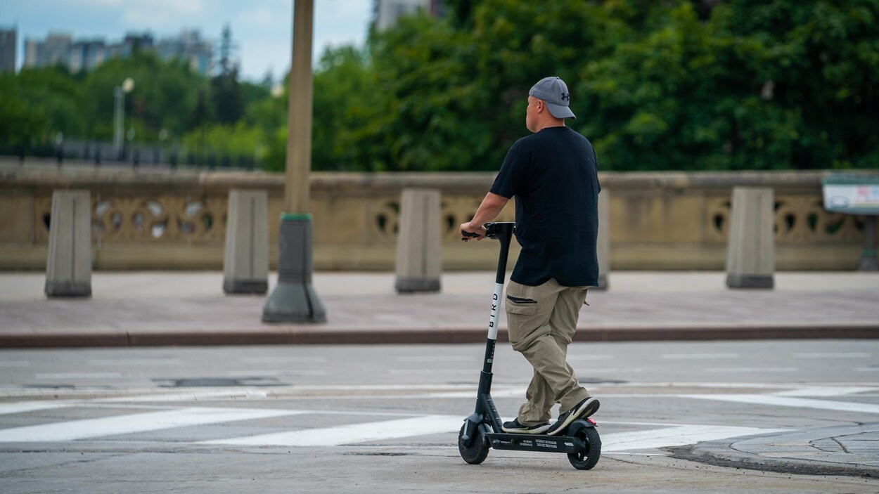 Un homme circule sur une trottinette au centre-ville.