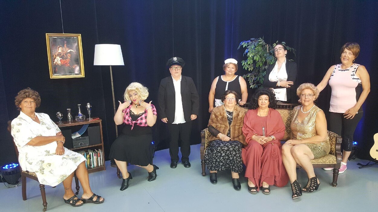 Neuf personnes en costume de théâtre posent dans un décor.