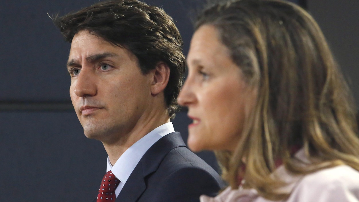 Justin Trudeau écoute Chrystia Freeland lors d'une conférence de presse
