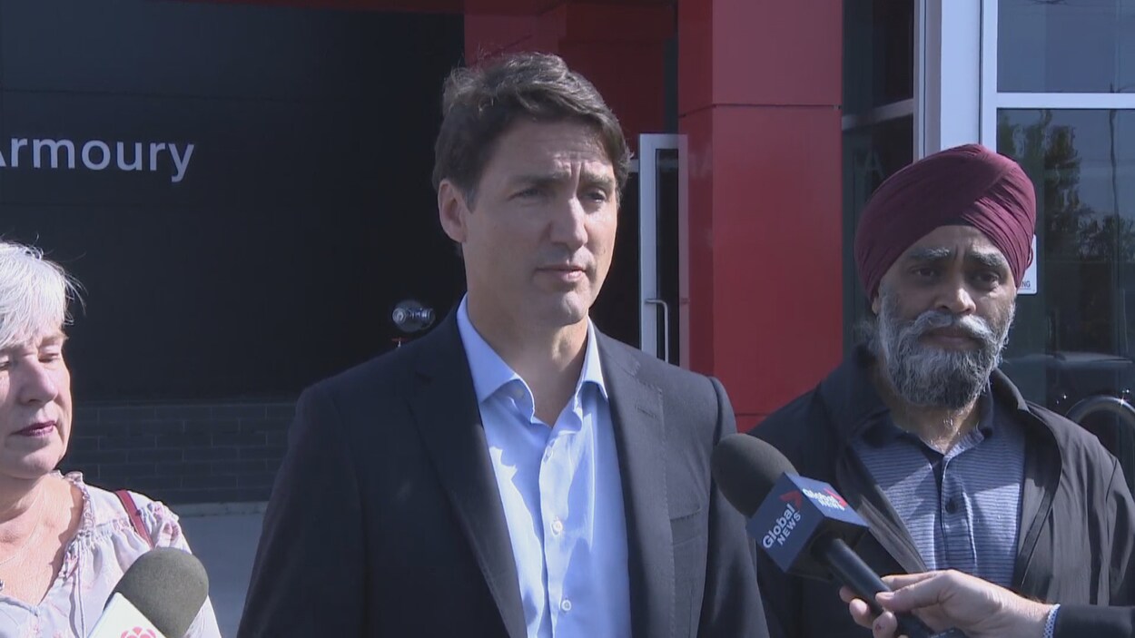 Justin Trudeau s'adresse aux journalistes avant d'entrer dans un bâtiment pour une réunion. On distingue à sa gauche le ministre de la Défense nationale, Harjit S. Sajjan.