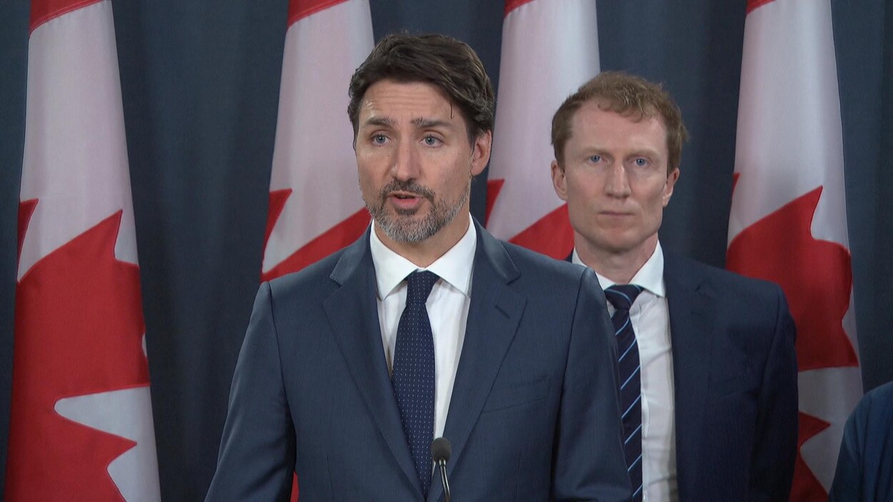 Justin Trudeau au micro, Marc Miller en arrière-plan.