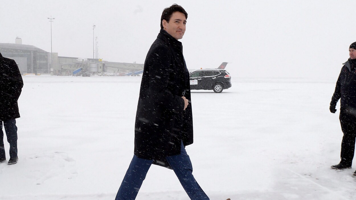 Le premier ministre Justin Trudeau marche dans la neige sur le tarmac d'un aéroport. Le premier ministre Justin Trudeau marche dans la neige sur le tarmac d'un aéroport.