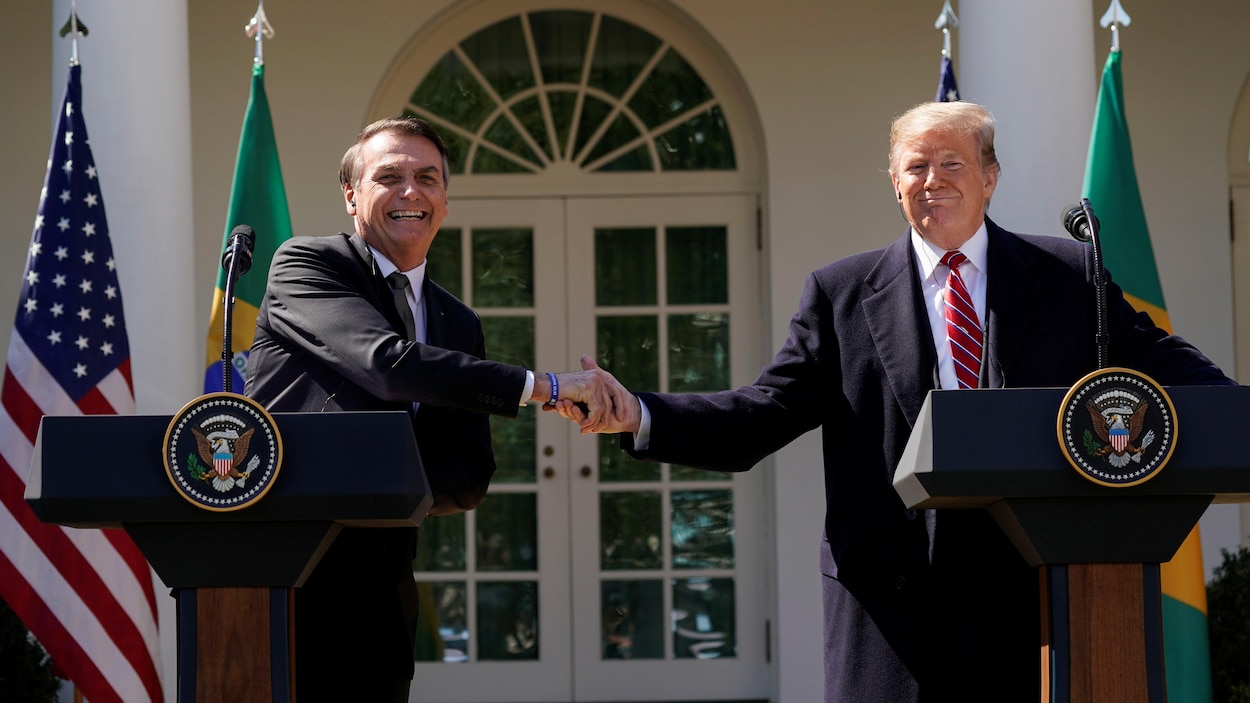 Tout sourire, Jair Bolsonaro et Donald Trump se serrent la main devant la Maison-Blanche.