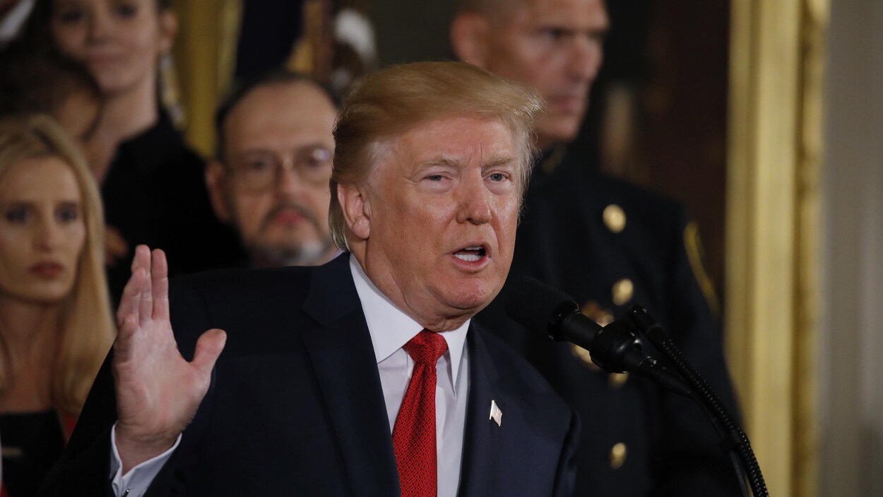 Le président des États-Unis, Donald Trump, la main droite levée, lors d'une allocution à la Maison-Blanche concernant la stratégie de son administration dans la lutte aux opioïdes