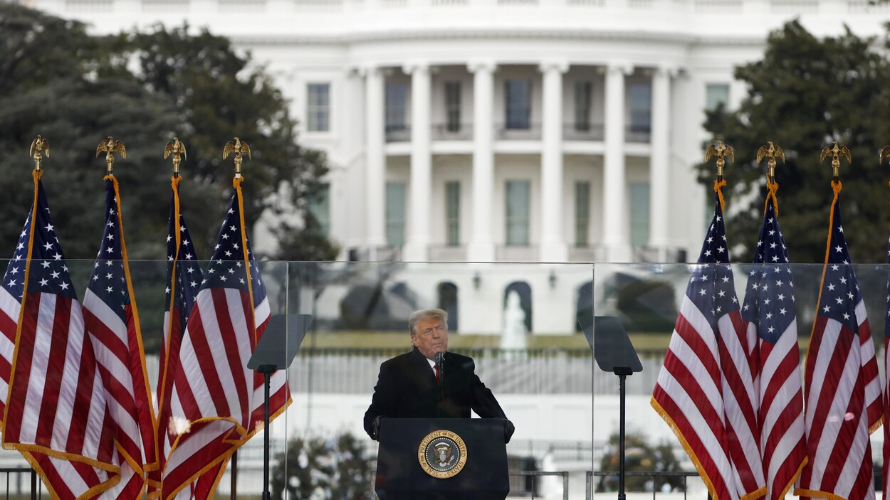 Donald Trump debout derrière un lutrin.