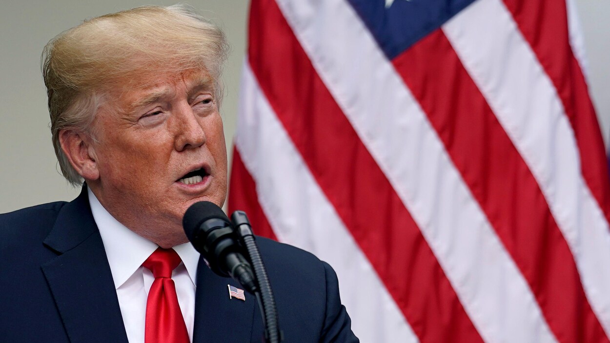 M. Trump est devant un drapeau des États-Unis.