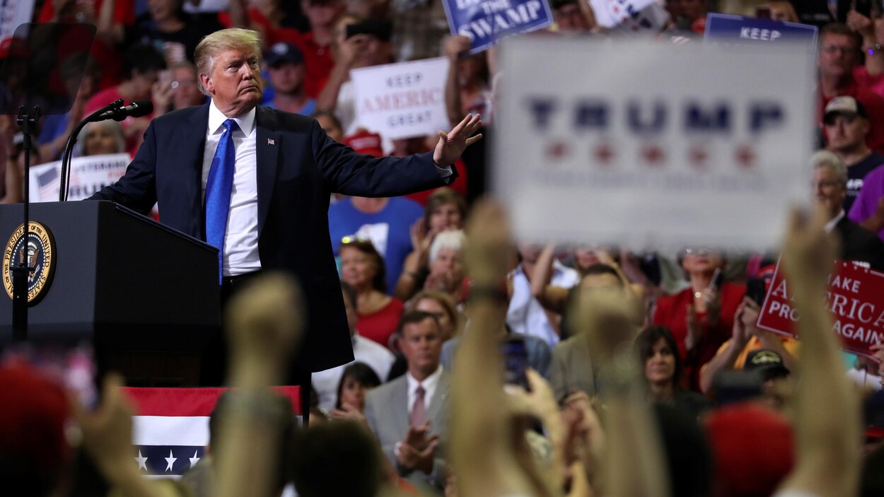 Le président Donald Trump se tourne vers des partisans au cours d'un rassemblement politique à Southaven, au Mississippi, alors que plusieurs d'entre eux brandissent des pancartes.
