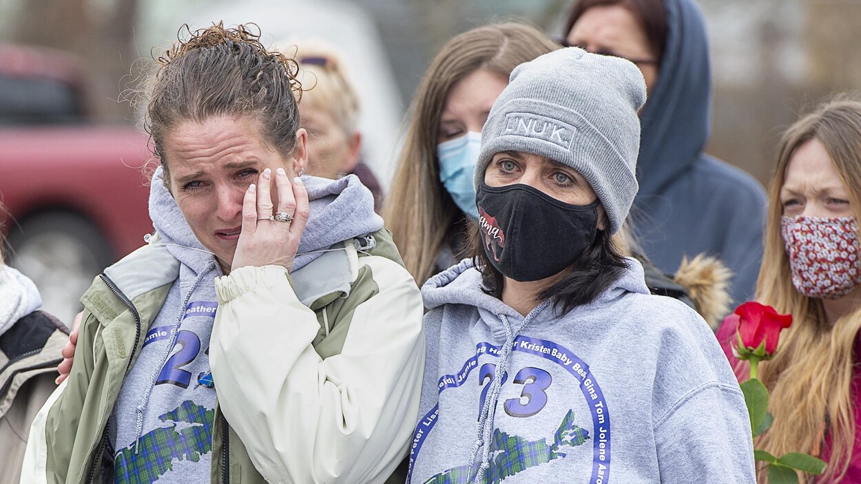 Une femme essuie ses larmes et est réconfortée par deux autres.