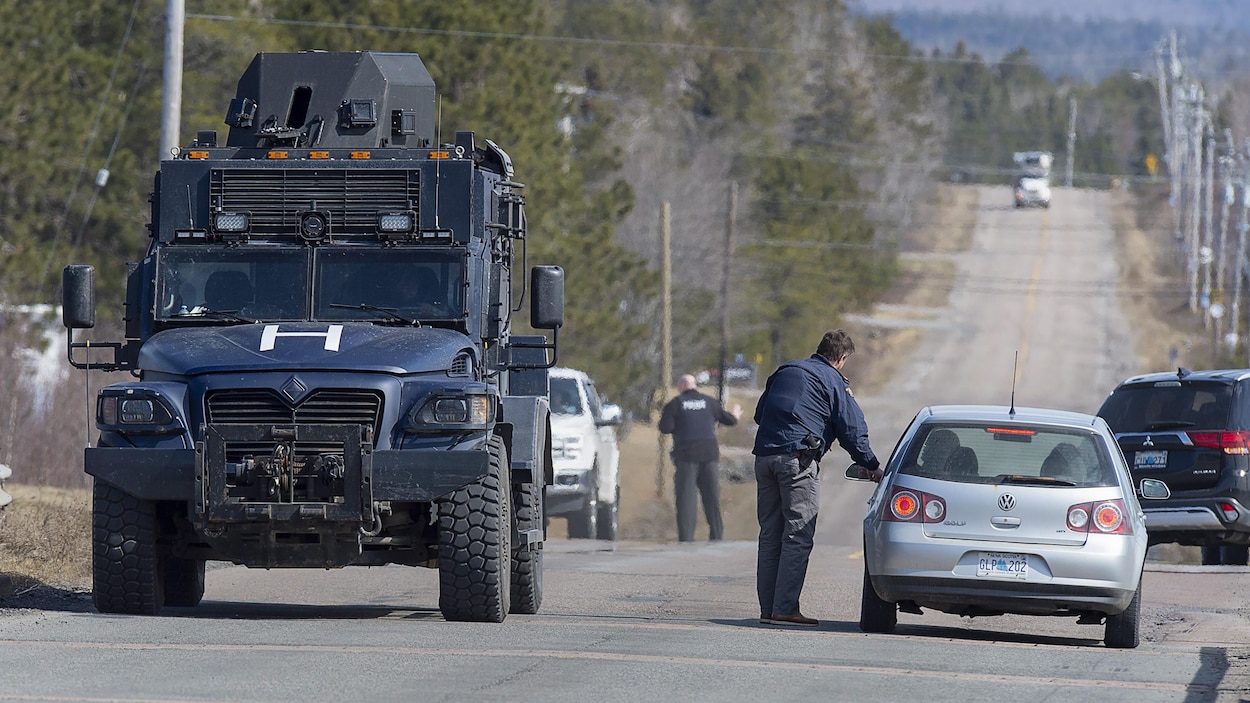 Un blindé de la police sur la route et des policiers qui interceptent des automobilistes.