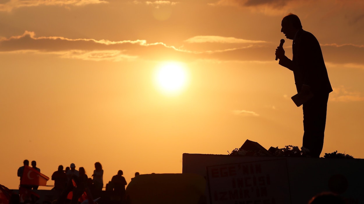 La silhouette d'un homme, micro à la main, avec en premier plan le soleil qui se couche. La silhouette d'un homme, micro à la main, avec en premier plan le soleil qui se couche.