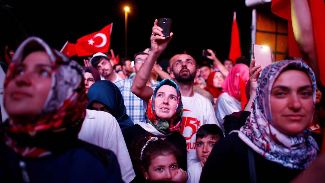 Des femmes, des hommes et des enfants semblent regarder au loin. Des drapeaux de la Turquie flottent autour d'eux. Des femmes, des hommes et des enfants semblent regarder au loin. Des drapeaux de la Turquie flottent autour d'eux.