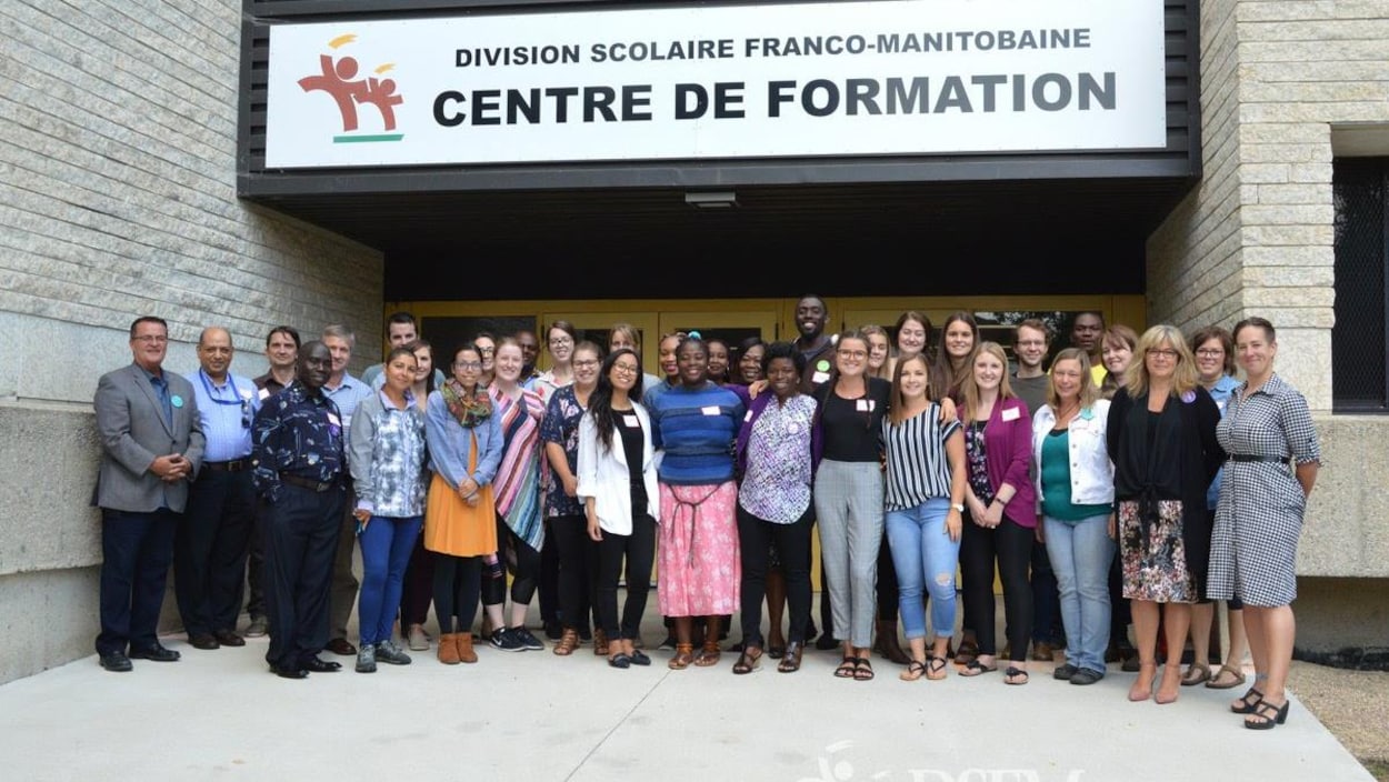 Devant le bâtiment de la DSFM, des adultes en groupe sourient à l'objectif.