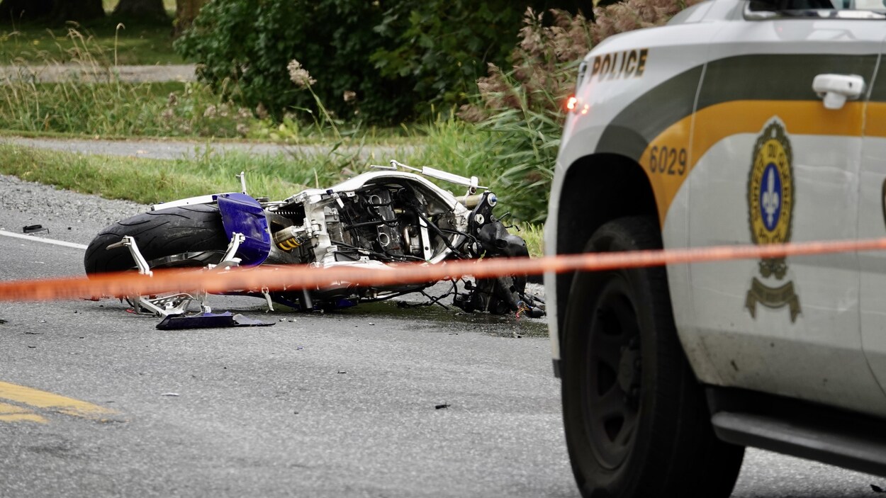 Une moto accidentée est couchée sur la route.