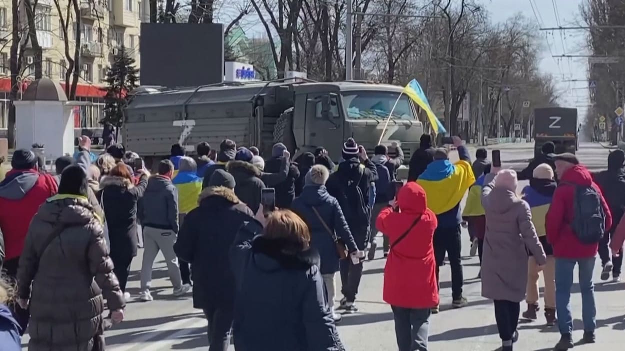 quelques manifestants face à un camion militaire