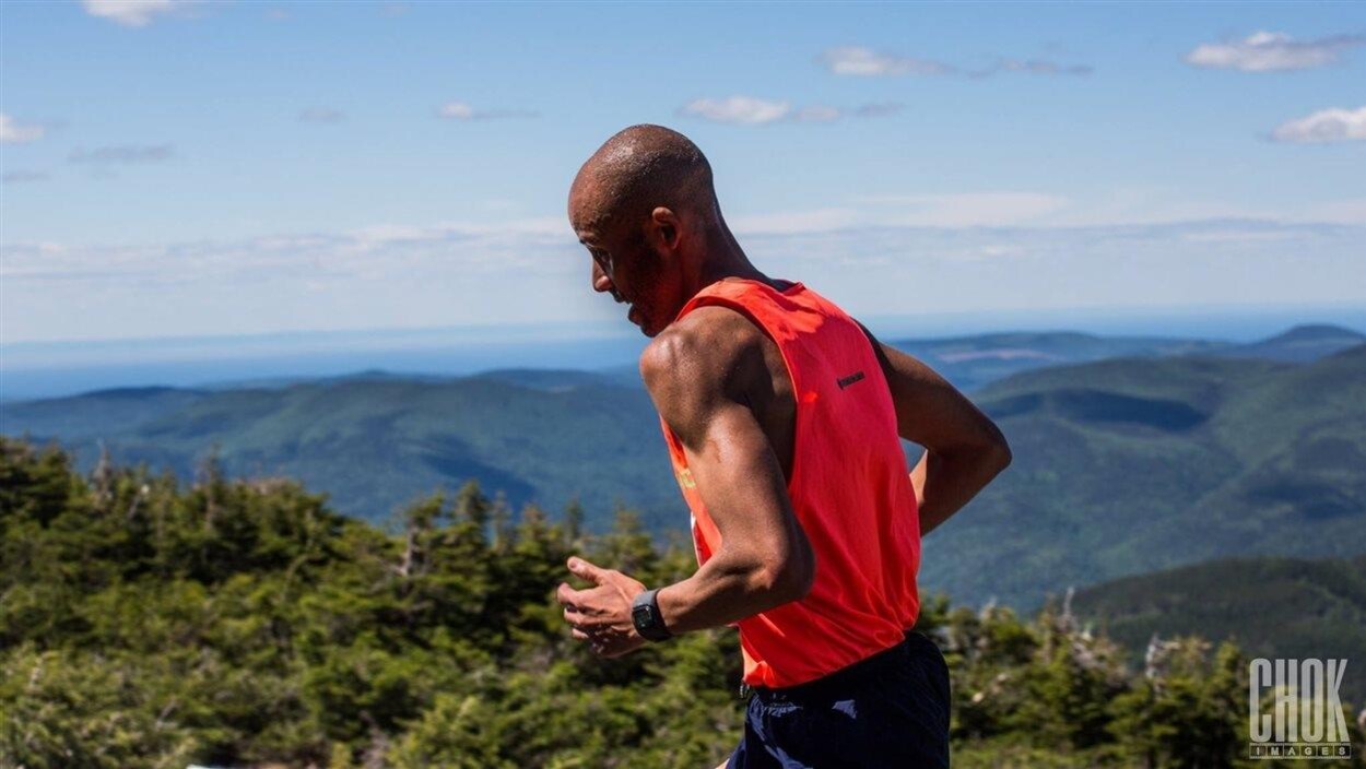 Un homme court au sommet d'une montagne qui domine le reste du paysage.