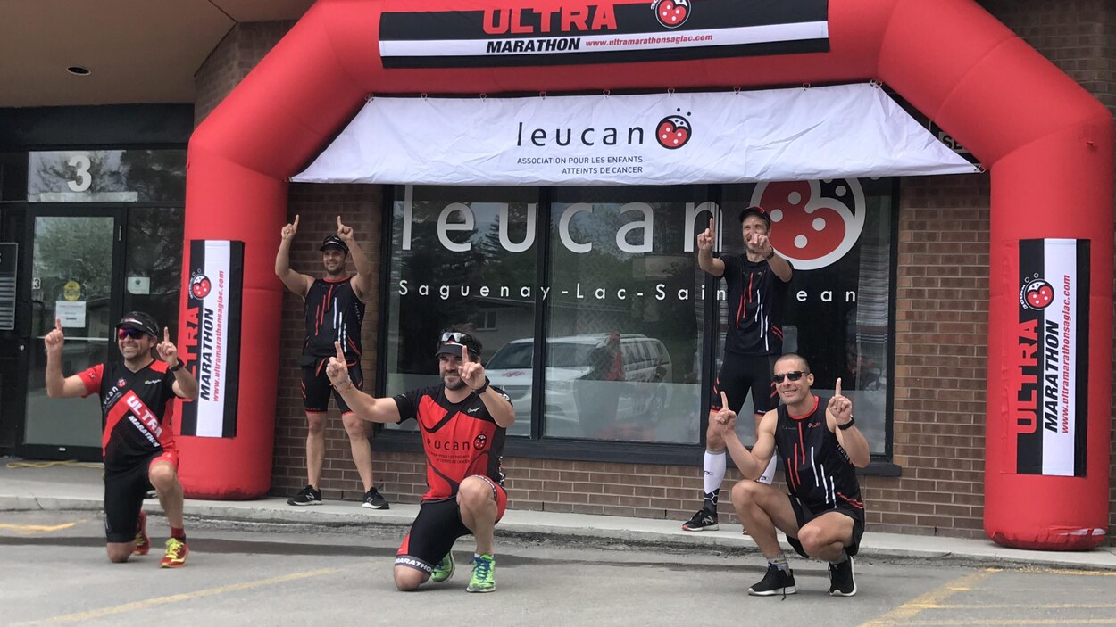 Cinq coureurs sous une arche d'arrivée.