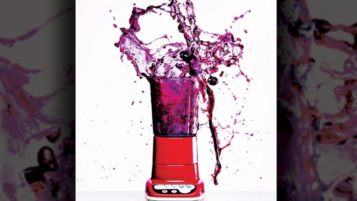 Photo d'un mélangeur rouge, couvercle ouvert, d'où s'échappe un liquide violet en giclant.