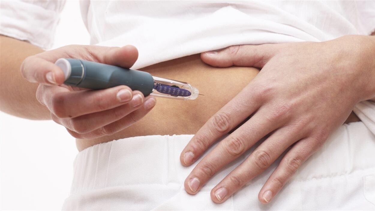 Une femme s'apprête à s'injecter une dose d'insuline dans l'abdomen.