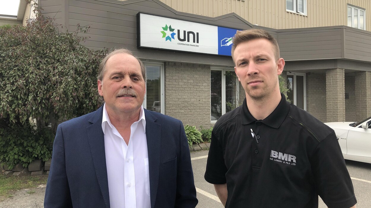 Deux hommes devant une caisse populaire dehors.