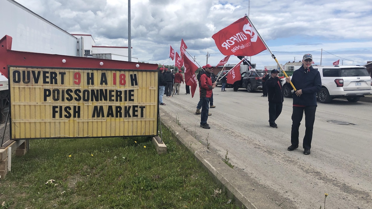 Des manifestants avec le drapeau du syndicat Unifor