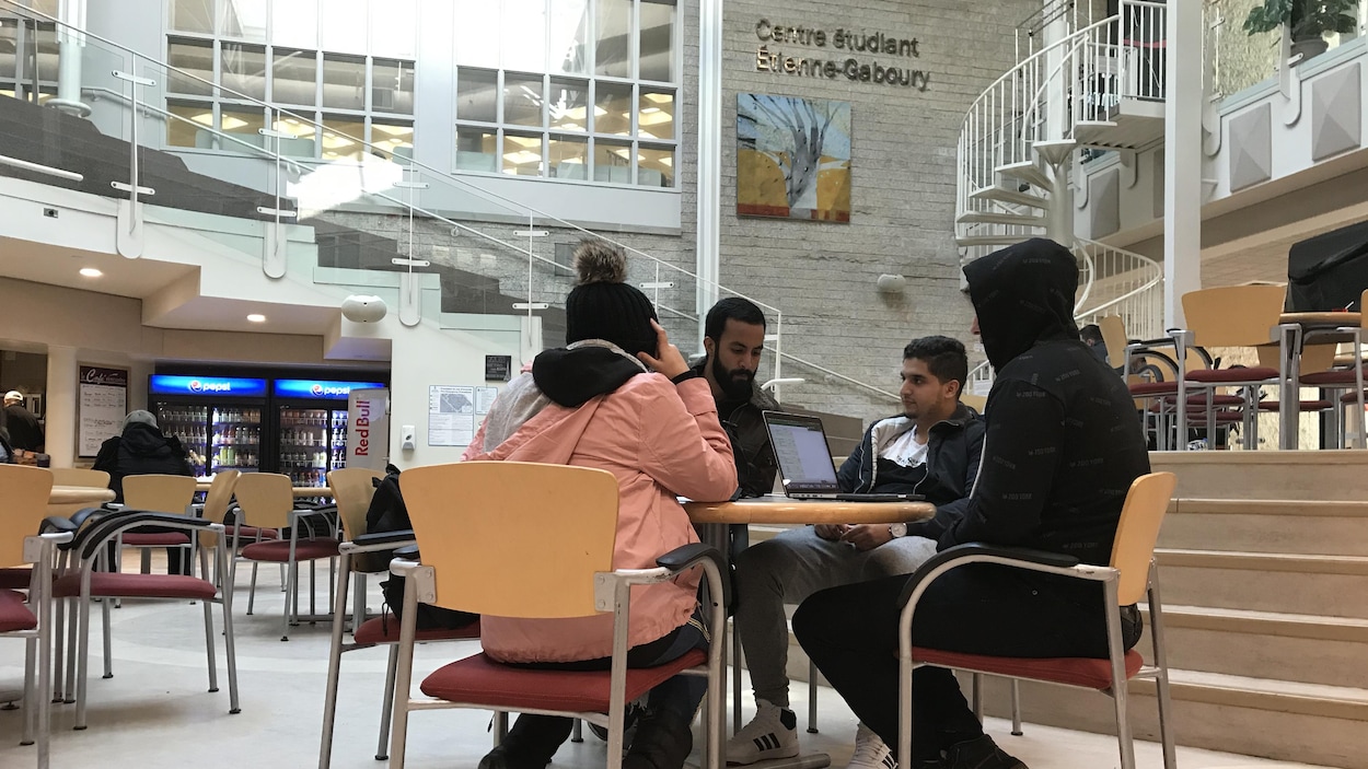 Quatre étudiants sont assis à une table dans la cafétéria de l'Université de Saint-Boniface.