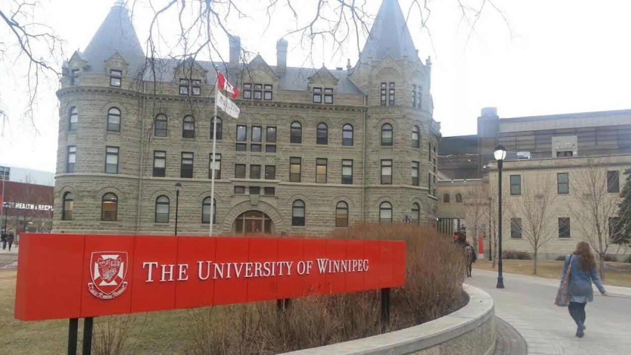 Une femme marche devant le bâtiment principal de l'Université de Winnipeg, rue Portage.