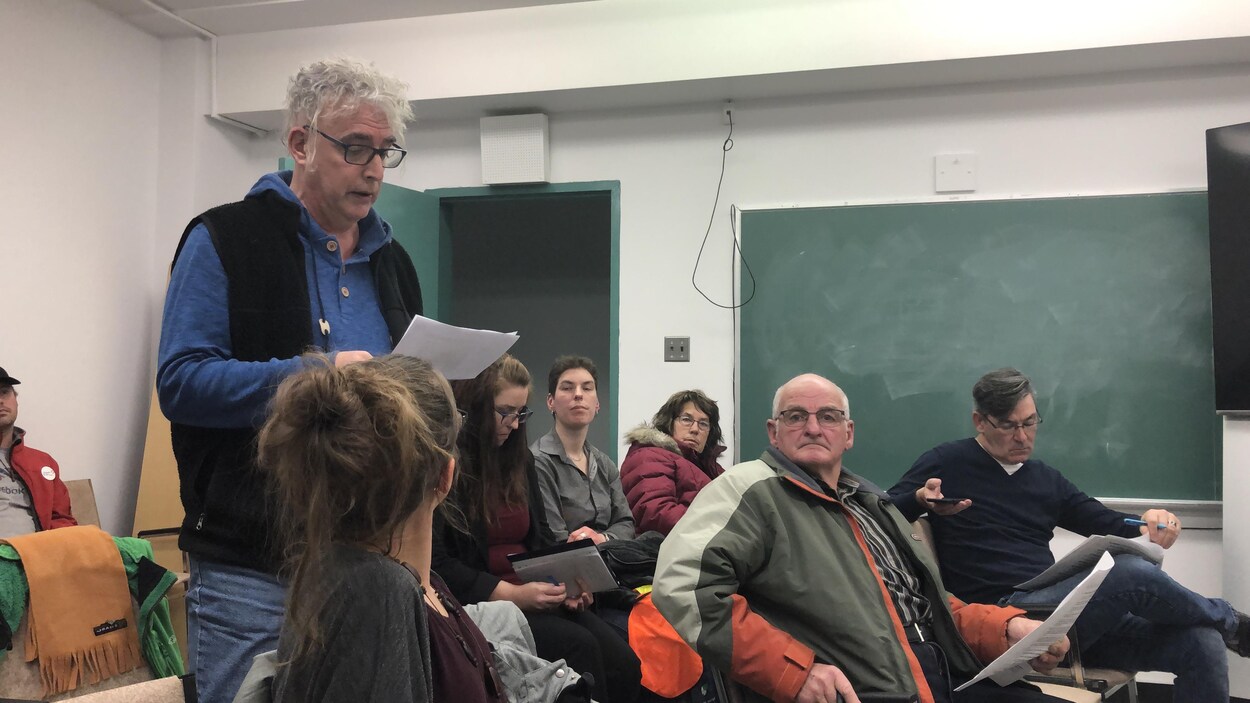 Un homme debout fait la lecture d'un document.