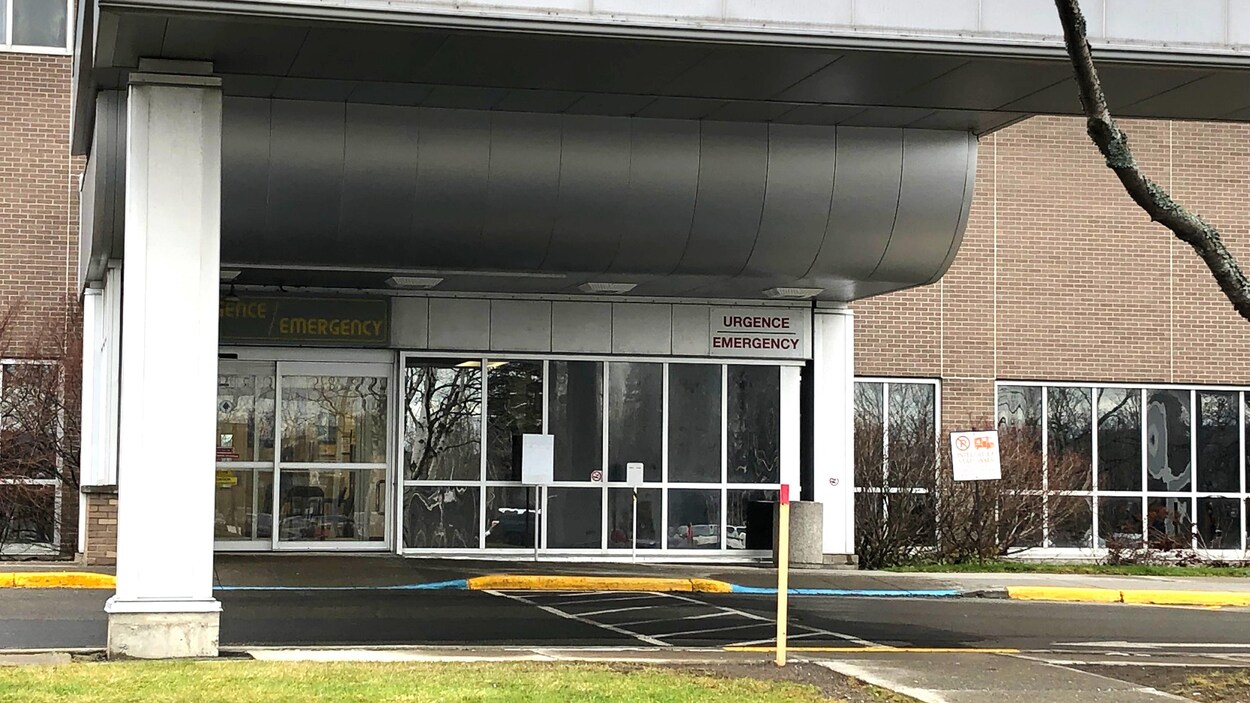 Les portes coulissantes automatiques de l'entrée de l'urgence d'un hôpital. Une enseigne « urgence » en lettres rouges est posée au-dessus des portes.