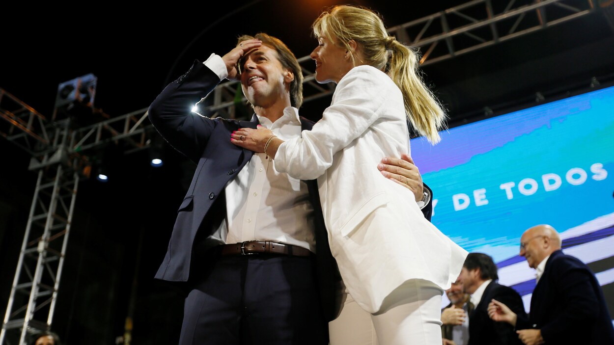 Un homme et une femme sur une scène avec des personnes en arrière plan.