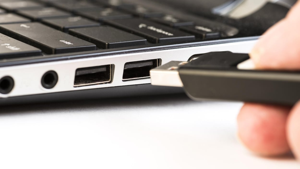 Une clé USB près des ports USB d'un ordinateur portable.