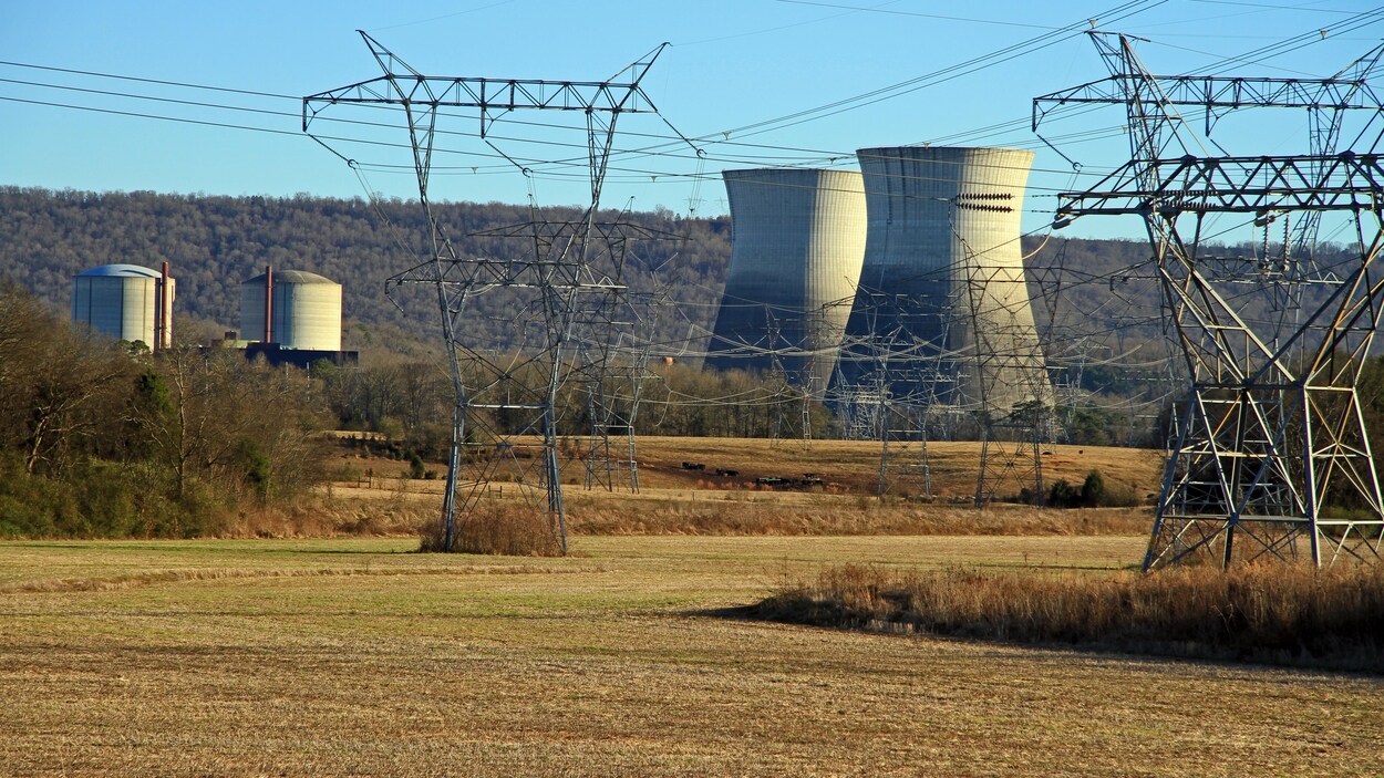 Une usine nucléaire à côté de pylônes électriques.