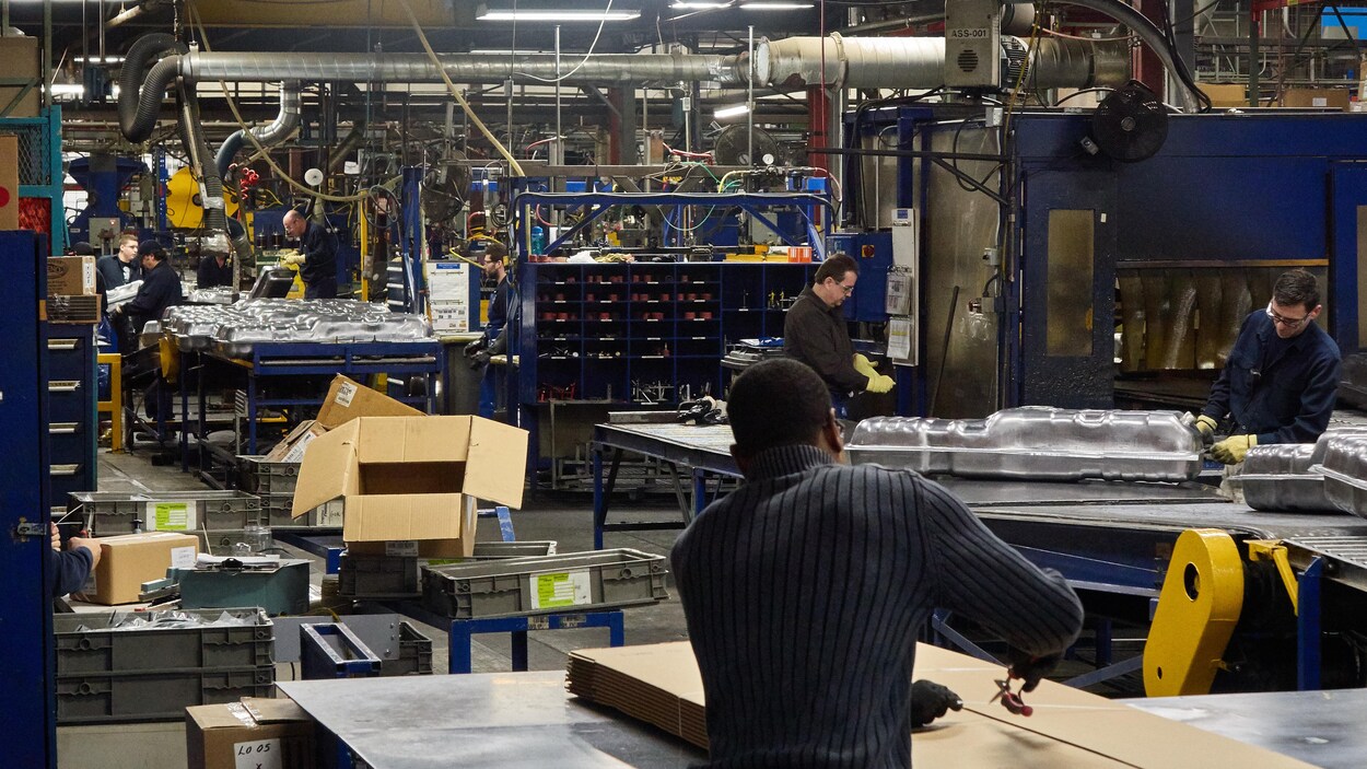 Des employés, certains de dos, certains de profil, qui travaillent à l'usine Spectra Premium de Boucherville.