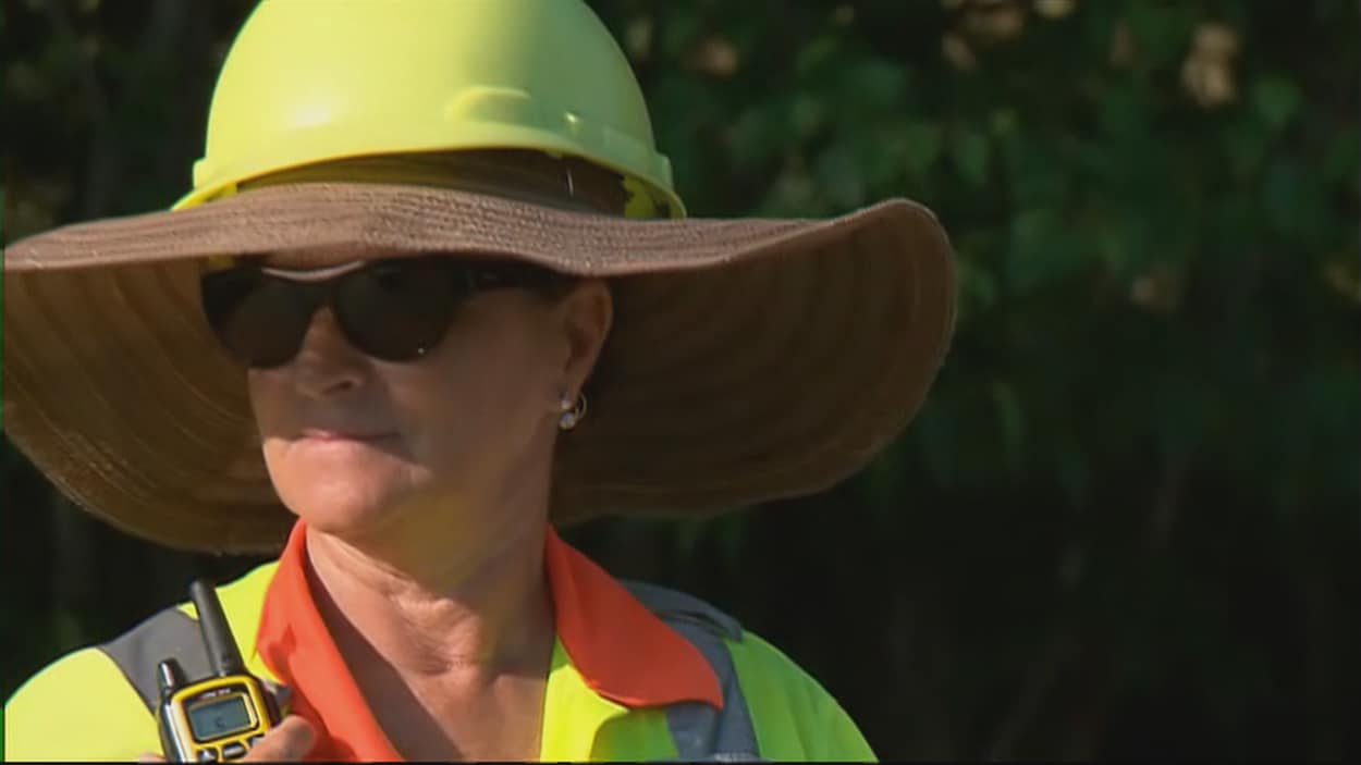 Une contrôleuse routier porte un chapeau de paille sous son casque de construction. Une contrôleuse routier porte un chapeau de paille sous son casque de construction.