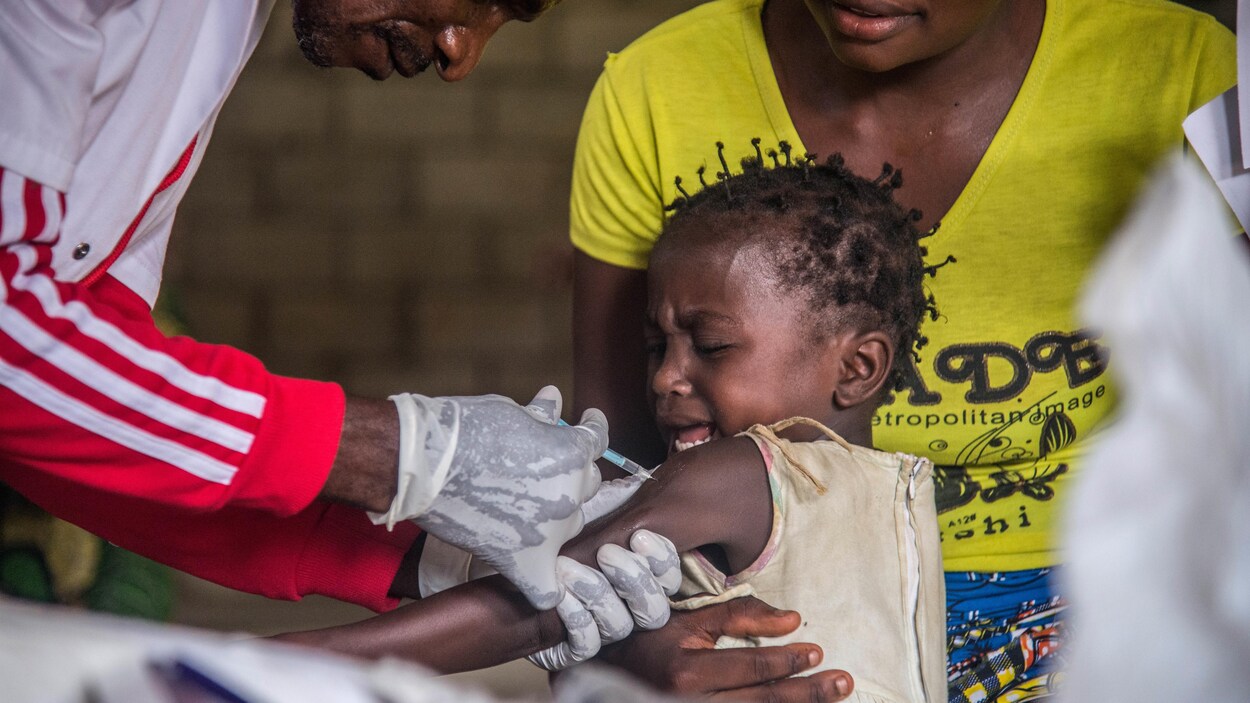 Un enfant assis sur les genoux de sa mère se fait vacciner