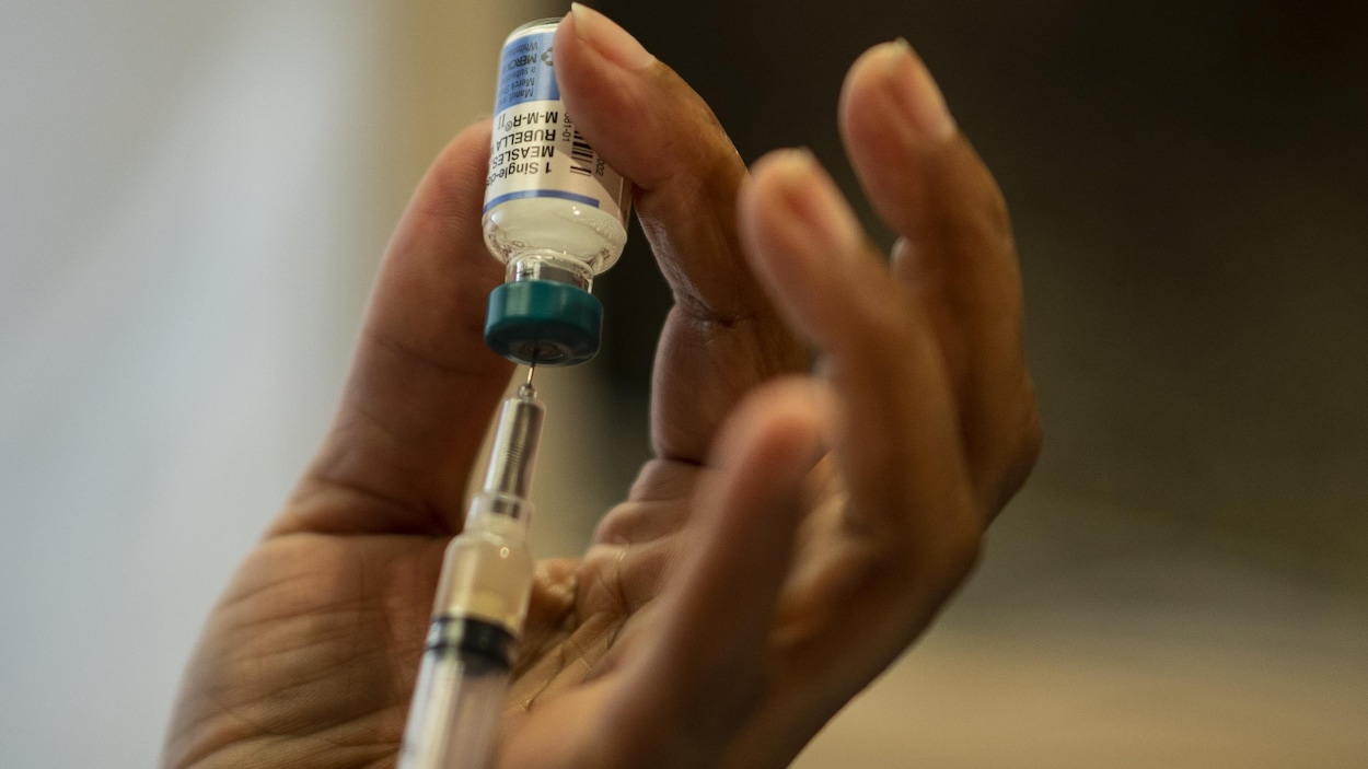 Gros plan sur la main d'une femme en train de préparer un vaccin.
